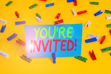 Writing note showing You Re Invited. Business concept for make a polite friendly request to someone go somewhere Colored clothespin papers empty reminder yellow floor background office