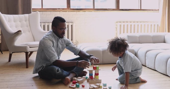 African dad teaching child son building constructor of wooden blocks