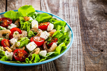 Salad with shrimps and feta cheese on wooden table