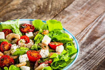 Salad with shrimps and feta cheese on wooden table