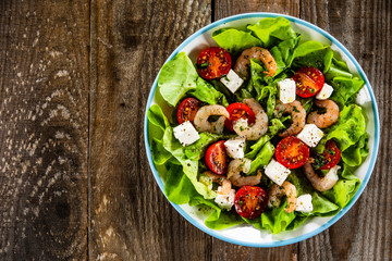 Salad with shrimps and feta cheese on wooden table