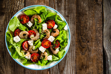 Salad with shrimps and feta cheese on wooden table