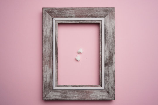 White pills with wooden frame on pink background