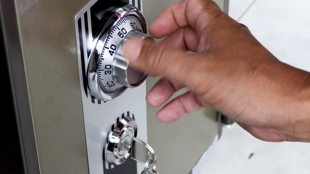 The man's hand is opening the safe door lock