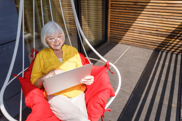 Happy adult female is using laptop outdoors