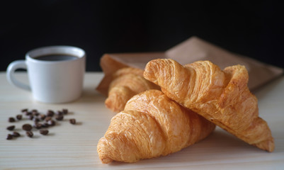Delicious breakfast with fresh croissants and cup of espresso coffee on wood table.