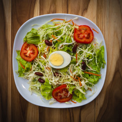 Salad bowls of vegetables and boiled eggs, healthy food on a wooden table.