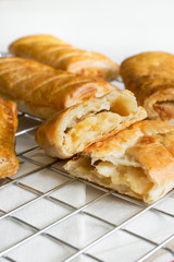 Savory cheese and onion puff pastry rolls fresh out of the oven cooling on a cooking trivet a vegetarian alternative to the usual sausage roll