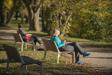Fototapeta premium Two women sitting in the colorful park in the autumn season