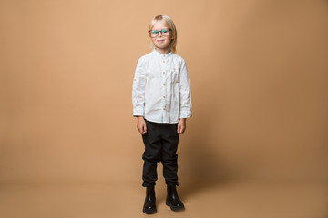 A boy in glasses dressed in white shirt, black trousers thinks about serious plans. School