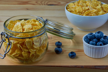 Cornflakes with milk for breakfast. Blueberries. Wood background.
