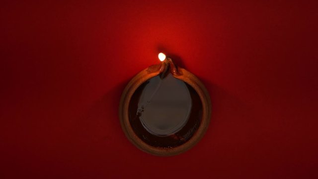 Festival lamp / diya aginst a red background