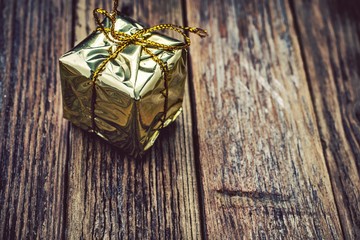 Gold gift box with gold thread on a wooden background
