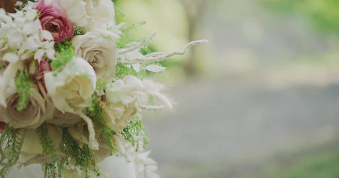 Close up detail shot of a brides hand holding a bouquet of roses as she walks in nature on her wedding day