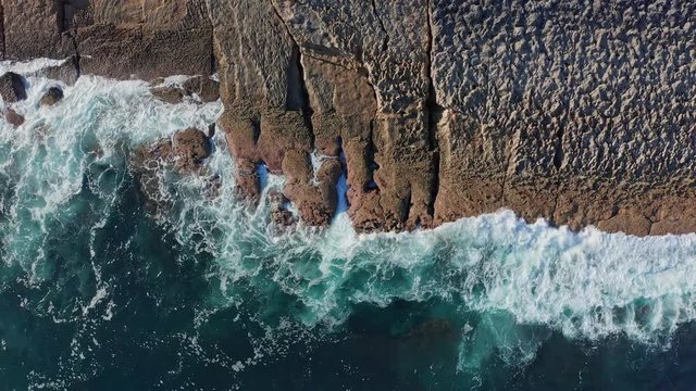 Ascending shot over sea waves breaking in the reefs and coast, Cantabrian sea, Spain - drone aerial view