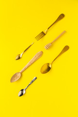 Spoons and forks on yellow background