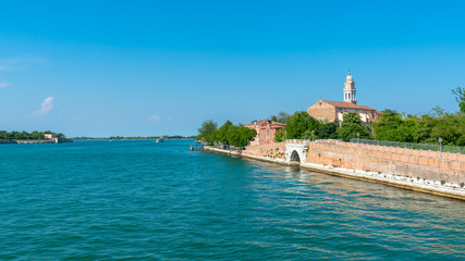 Venice. Island Lido. Panoramic view of beautiful embankment of Lido island with Saint Nicolas Church. Blue sky and green trees background. 