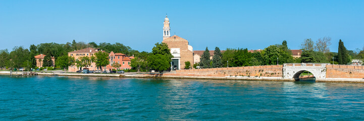 Naklejka premium Venice. Island Lido. Panoramic view of beautiful embankment of Lido island with Saint Nicolas Church. Blue sky and green trees background. Header. Banner. 