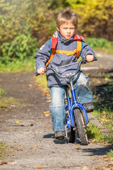 Little boy rides a bicycle in the autumn park.