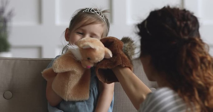 Cute small kid girl holding puppet toy playing with mother
