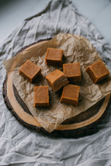Fresh caramel fudge candies on a wooden plate with copy space in marble background