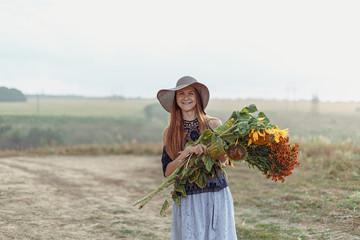 Red girl with flowers in a field in the rain