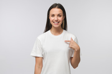 Young woman pointing with index finger at blank t-shirt with empty space for your advertising text...