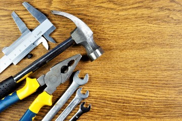 Master tool on wooden background, fathers day holiday. Popular locksmith tools for construction creativity and business-carpenter's hammer, pliers mechanic, wrenches, calipers.