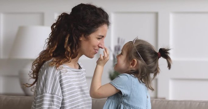 Happy mom and little child daughter touching noses laughing bonding