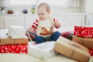 Happy little baby girl opening Christmas presents on her very first Christmas