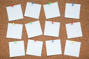 a sheets of paper are attached to the cork Board with a push-buttons. empty note papers pinned on...