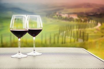 two glasses of red wine against beautiful landscape in Tuscany