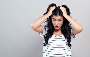 Young woman feeling stressed on a gray background