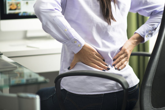 Woman sitting at office having back pain due to bad position or having a not ergonomic chair