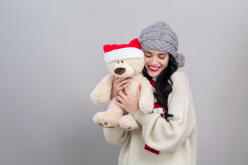 Obraz premium Young woman holding a teddy bear on a gray background