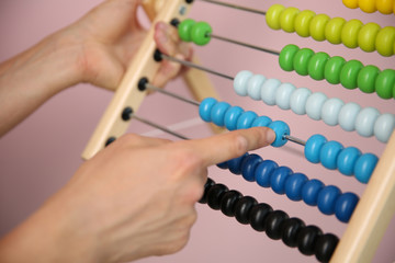 female's hands count on multi-colored abacus. human uses children's abacus close up