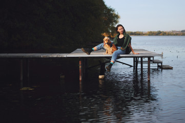 Girl with her dog, English Cocker Spaniel, sitting on the bench near the lake
