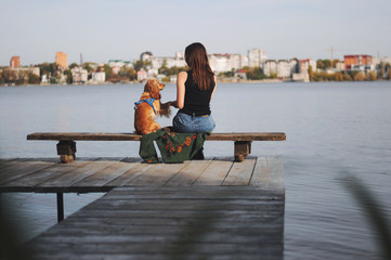 Girl with her dog, English Cocker Spaniel, sitting on the bench near the lake