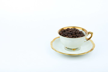 roasted coffee beans in a white porcelain cup on white background with copy space