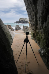 Camera on a tripod standing between massive rocks at a north atlantic beach near bilbao and santander in spain. Photographer taking pictures of rock formations at flysch beach.