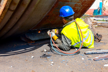 Worker is cutting old metal industrial equipment with acetylene torch