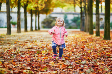 Adorable cheerful toddler girl running in Tuileries garden in Paris, France