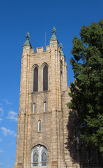 Fototapeta na wymiar Stone Church Bell Tower by Tree on Clear Blue Sky