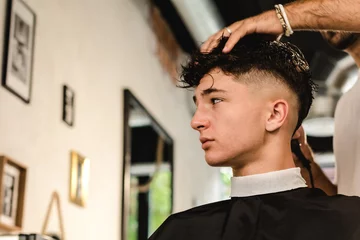 Fotobehang Kapsalon Teenager getting a modern haircut in a vintage barber shop  © DMegias