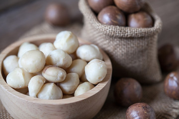 Macadamia nuts on sackcloth and wooden background