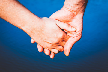 couple holding hands over blue water background