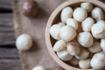 Macadamia nuts on sackcloth and wooden background
