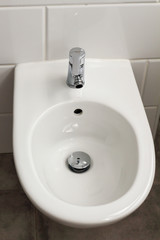 White hanging bidet seat in the hotel house bathroom with white tiles  on the wall. Bathroom luxury modern interior 