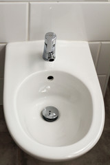 White hanging bidet seat in the hotel house bathroom with white tiles  on the wall. Bathroom luxury modern interior 