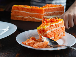 three bitten piece of carrot cake lies on a white plate. Children's hand in the frame.